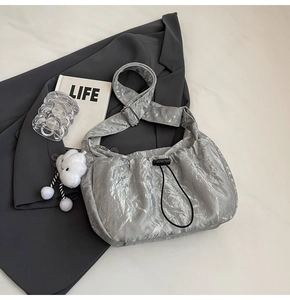 Detailed shot of silver pleated crossbody bag with drawstring and white cloud pendant