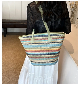 Close-up of a colorful striped woven tote bag featuring reinforced green leather straps
