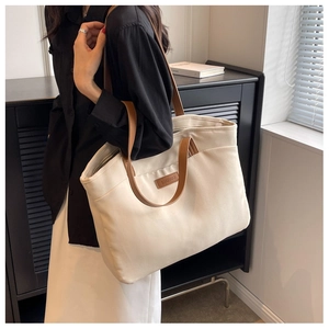 Detailed shot of large canvas tote bag in cream white with brown leather handles