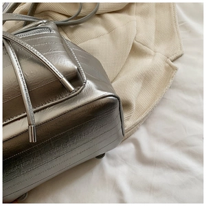 Detailed view of silver metallic leather texture and delicate drawstring on fashion backpack