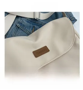 Close-up of the vintage canvas shoulder bag featuring a brown leather logo patch