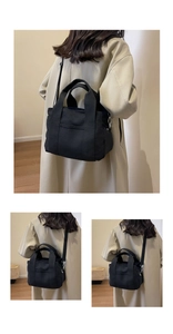 Detailed macro view of black canvas tote bag showing the front pocket and adjustable strap