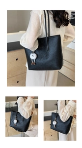 Close-up of black leather tote with cartoon heart embossing and furry monster charm