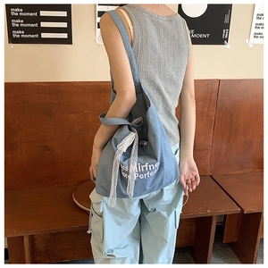 Detail view of denim tote bag featuring white lace bow and elegant letter embroidery