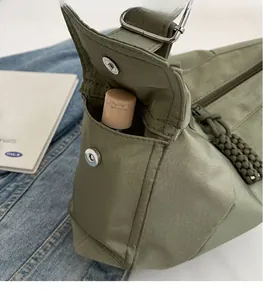Dettaglio della borsa a tracolla in nylon verde militare con tasca e bottone in metallo