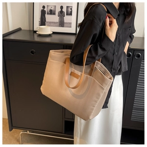 Detail of color-block canvas tote bag with brown leather handles and brand logo