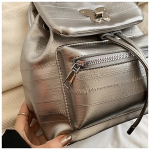 Detail showing metallic silver backpack texture with butterfly metal buckle and front pocket
