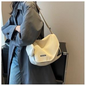 Vue détaillée du sac bandoulière crème en toile avec étiquette tissée et petite pochette
