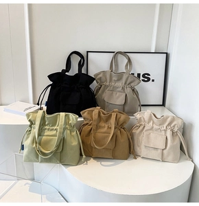 Group display of five canvas tote bags in black, grey, green, brown, and cream white