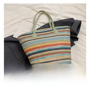 Detail view of colorful woven straw tote bag with multi-color stripes and green faux leather handles