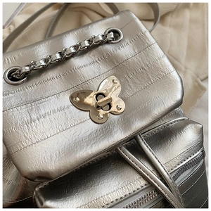 Detail of silver metallic backpack featuring butterfly metal clasp and chain decor