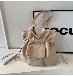 Detail of cream corduroy tote bag showing soft ribbed texture and drawstring closure