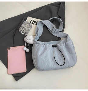 Close-up of light blue wrinkled nylon bag with black drawstring and cloud plush charm