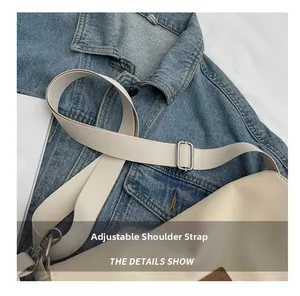 Detail showing adjustable woven wide strap with silver metal buckle on a beige canvas bag