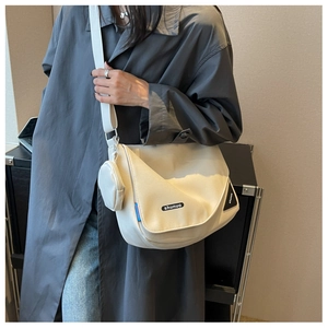 Gros plan sur le sac messager en toile blanche avec mini porte-monnaie et logo imprimé