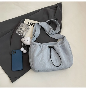 Macro shot of light blue ruched crossbody bag with drawstring closure and cloud pendant