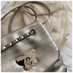 Detail of silver metallic leather bag with butterfly twist lock and chain strap