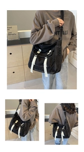 Detail of black canvas messenger bag featuring contrast white straps and buckle closure