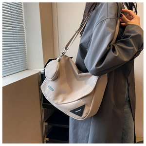 Détail d'une besace en toile kaki avec mini pochette amovible et écusson logo moderne