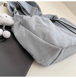 Detailed view of the light grey shoulder bag featuring unique paper-like textured fabric