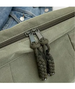 Dettaglio della borsa in nylon verde oliva con doppie cerniere in metallo e tiranti intrecciati