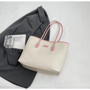 Close-up of beige tote bag with pink straps and 3D cartoon embossed details