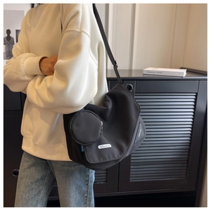 Détail du grand sac bandoulière noir minimaliste avec pendentif rond et sangle réglable