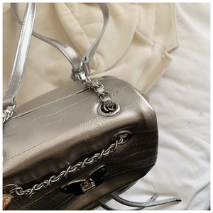 Close-up of silver butterfly twist lock and metallic chain on cracked texture backpack