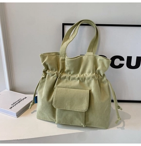Detail of light green corduroy tote bag featuring drawstring closure and front flap pocket