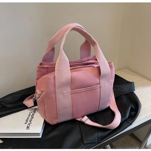 Detail of pink canvas tote showing adjustable shoulder strap with silver metal buckle