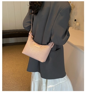 Gros plan détaillé d'un sac baguette demi-lune rose tissé sur un mannequin en costume gris
