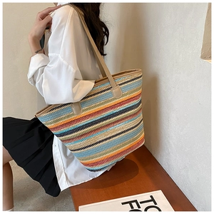 Detail of colorful striped straw tote bag showing large capacity and leather shoulder straps