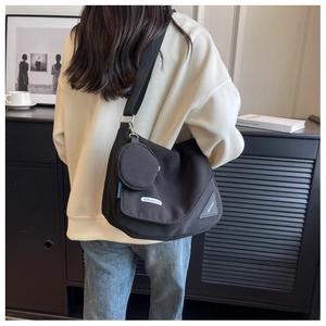 Vue détaillée du grand sac en toile noire avec bandoulière et mini pochette ronde