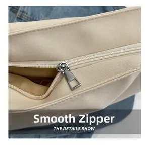 Detailed macro view of the smooth metal zipper and canvas texture on a cream shoulder bag