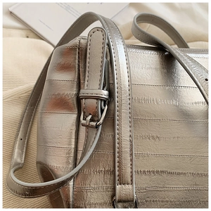 Detail of silver metallic textured leather bag showing adjustable buckle and fine stitching