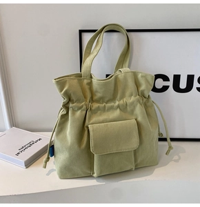 Close-up of light green corduroy tote bag featuring drawstring closure and front pocket