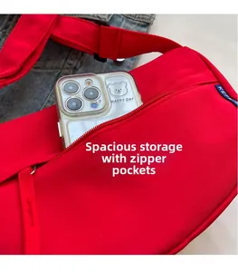 Detail of red crossbody bag showing front zipper pocket and spacious inner compartment