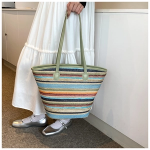 Close-up of a large woven tote bag with colorful stripes and light green shoulder straps