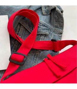 Detail of red nylon bag showing adjustable wide shoulder strap and black plastic buckle