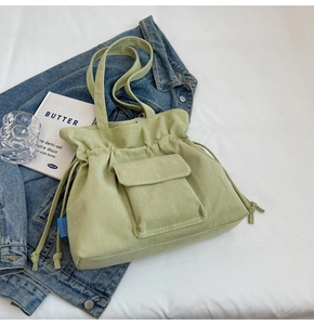 Detalle del bolso tote de pana verde menta con cordón lateral y bolsillo frontal