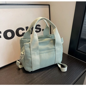 Detailed close-up of mint green canvas tote bag with adjustable strap and silver hardware