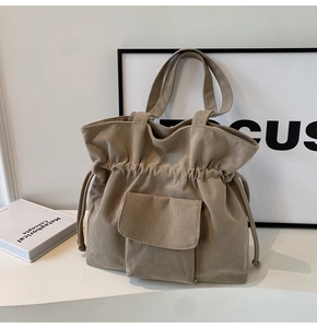 Detailed close-up of khaki corduroy tote bag featuring drawstring closure and front pocket