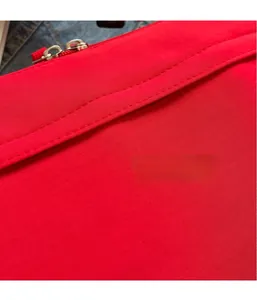 Detail of red water-resistant nylon fabric with precise stitching and metal zipper hardware