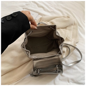 Close-up of silver PU leather backpack with chain strap and metallic drawstring detail