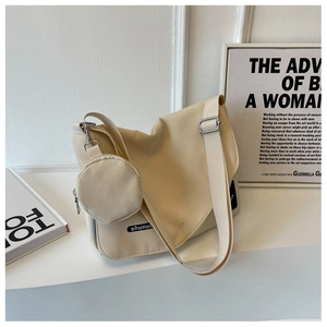 Détail du sac messager en toile beige avec bandoulière et petit porte-monnaie rond