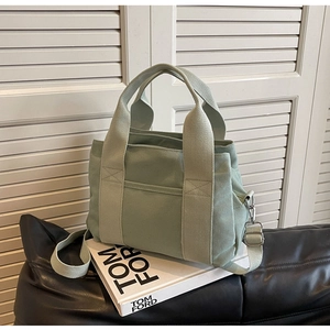 Detailed close-up of light green canvas tote with adjustable strap and front pocket