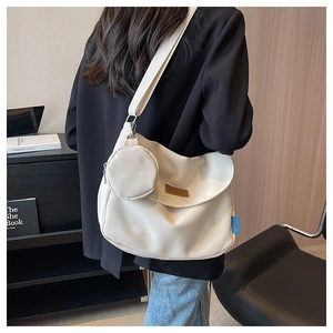 Detail of minimalist cream canvas shoulder bag with brown leather logo and round coin purse
