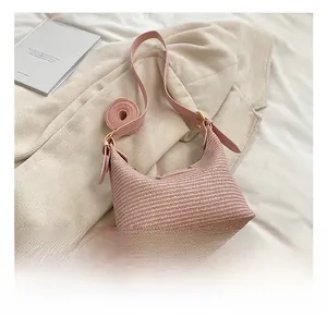 Détail du sac demi-lune tressé rose avec bandoulière en cuir et boucle dorée chic