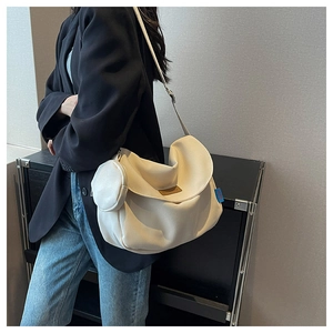 Detail of a large cream crossbody bag with a round coin pouch on a female model