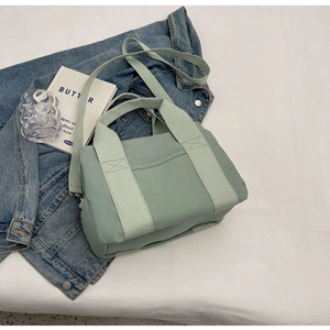 Detail of light green canvas tote bag on denim jacket with lifestyle accessories